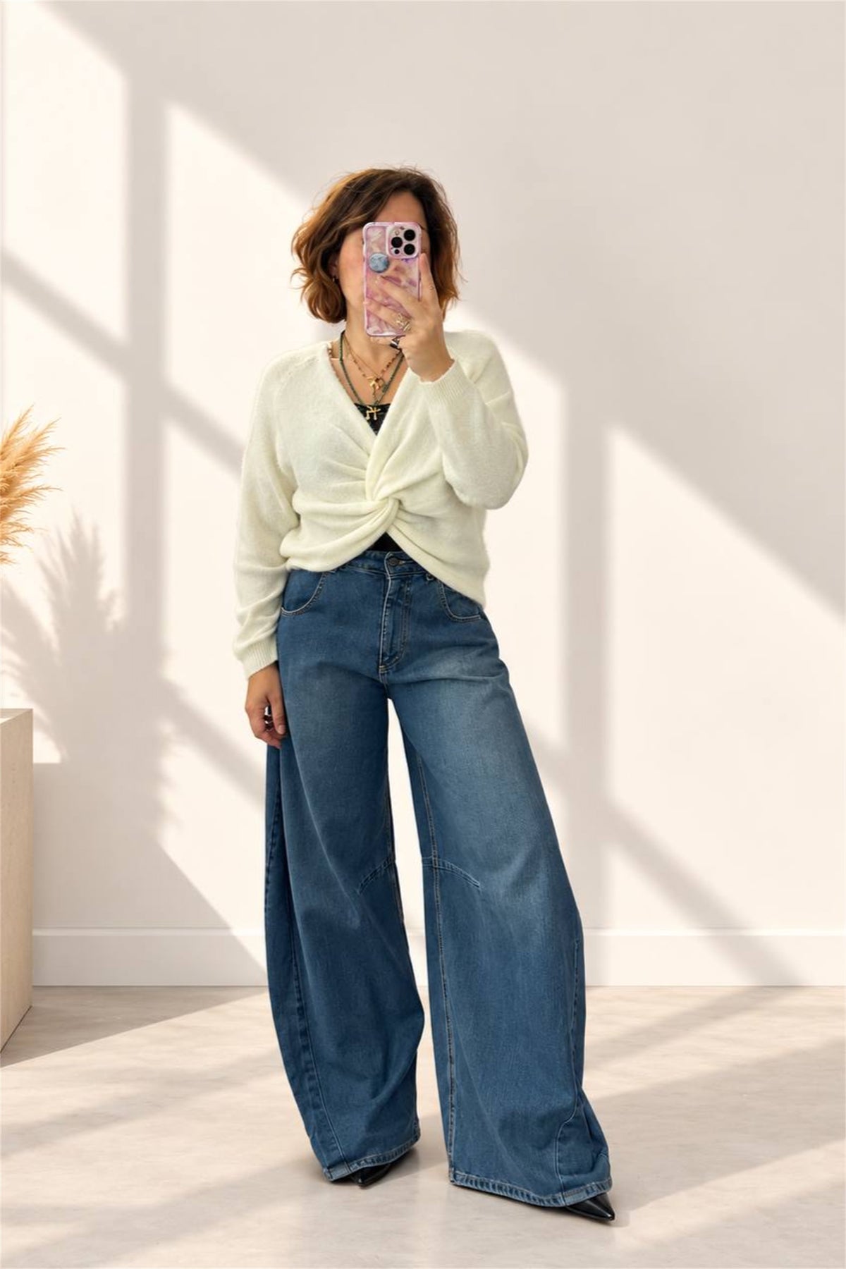Donna indossa maglia panna con nodo davanti e jeans ampi, vista frontale
