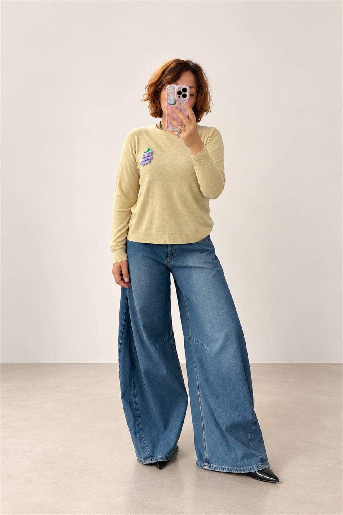 Donna indossa maglione beige melange con jeans ampi, vista frontale intera