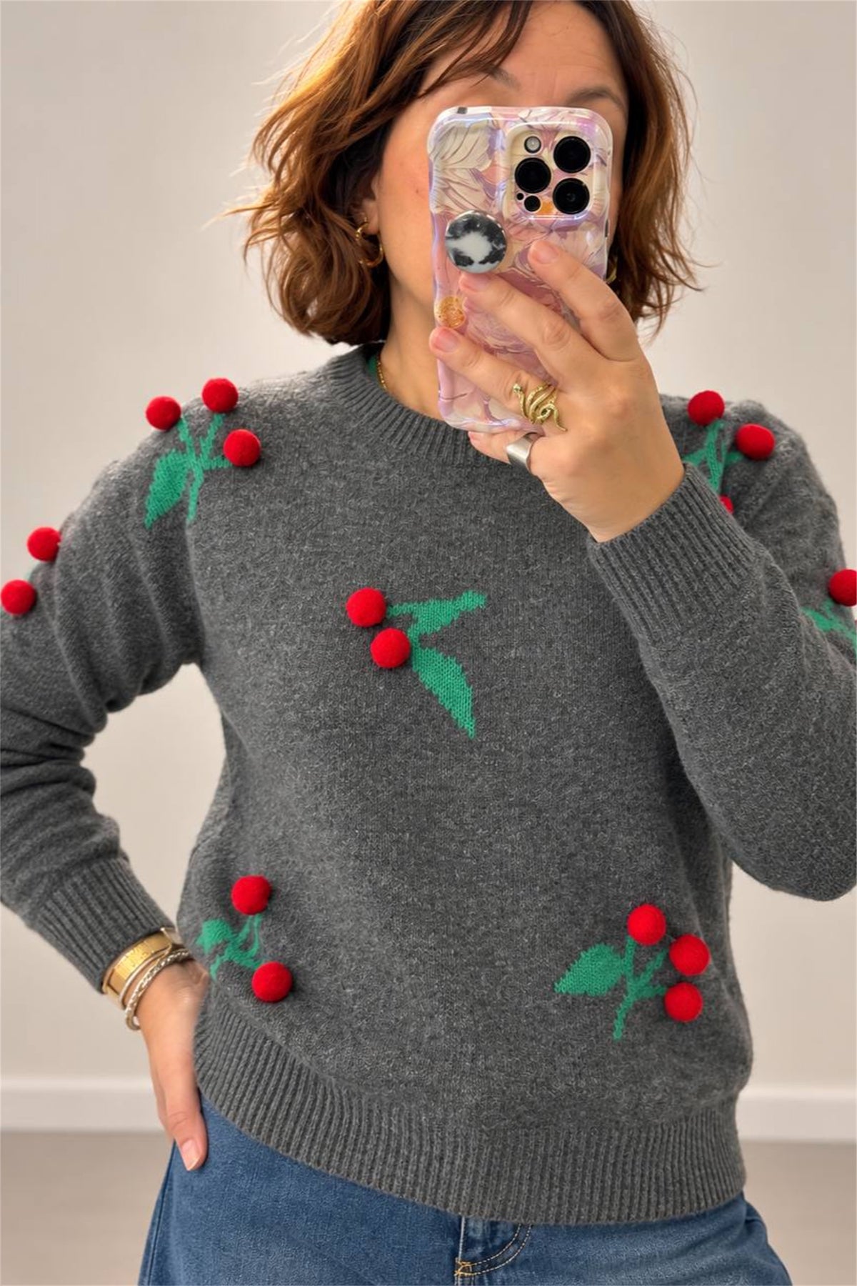 Maglia grigia con bacche a pom pom, vista frontale da vicino