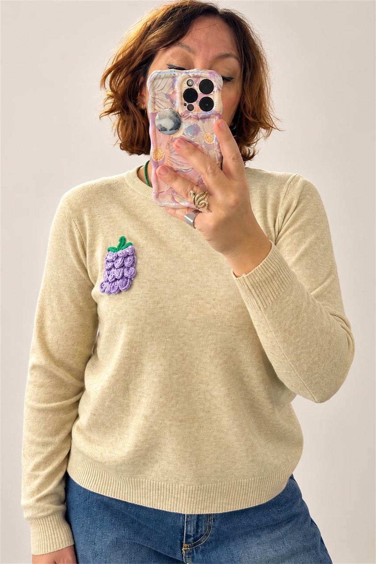 Maglione beige melange con grappolo d'uva applicato, vista frontale ravvicinata