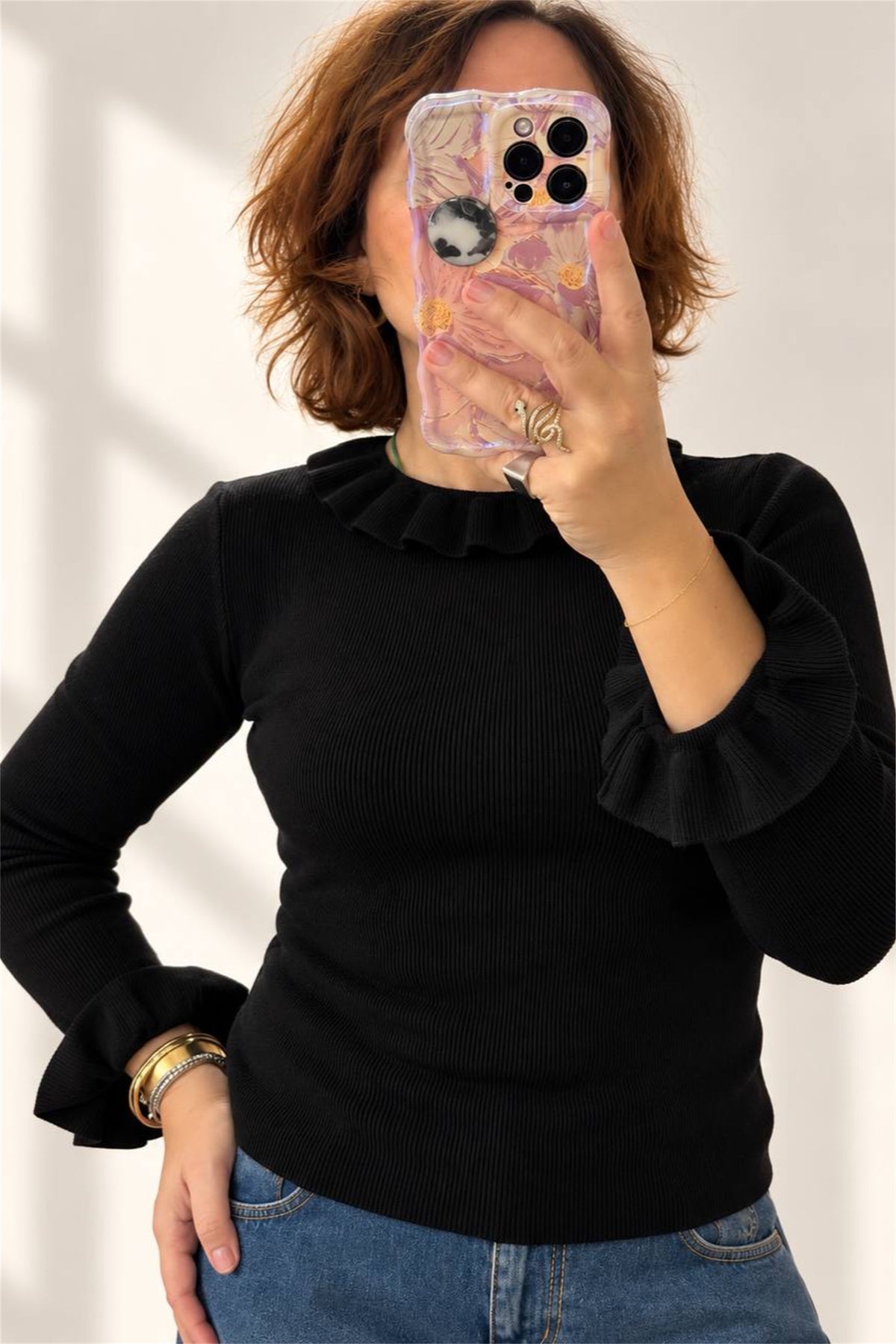 Dettaglio del polsino con rouches sulla maglia nera