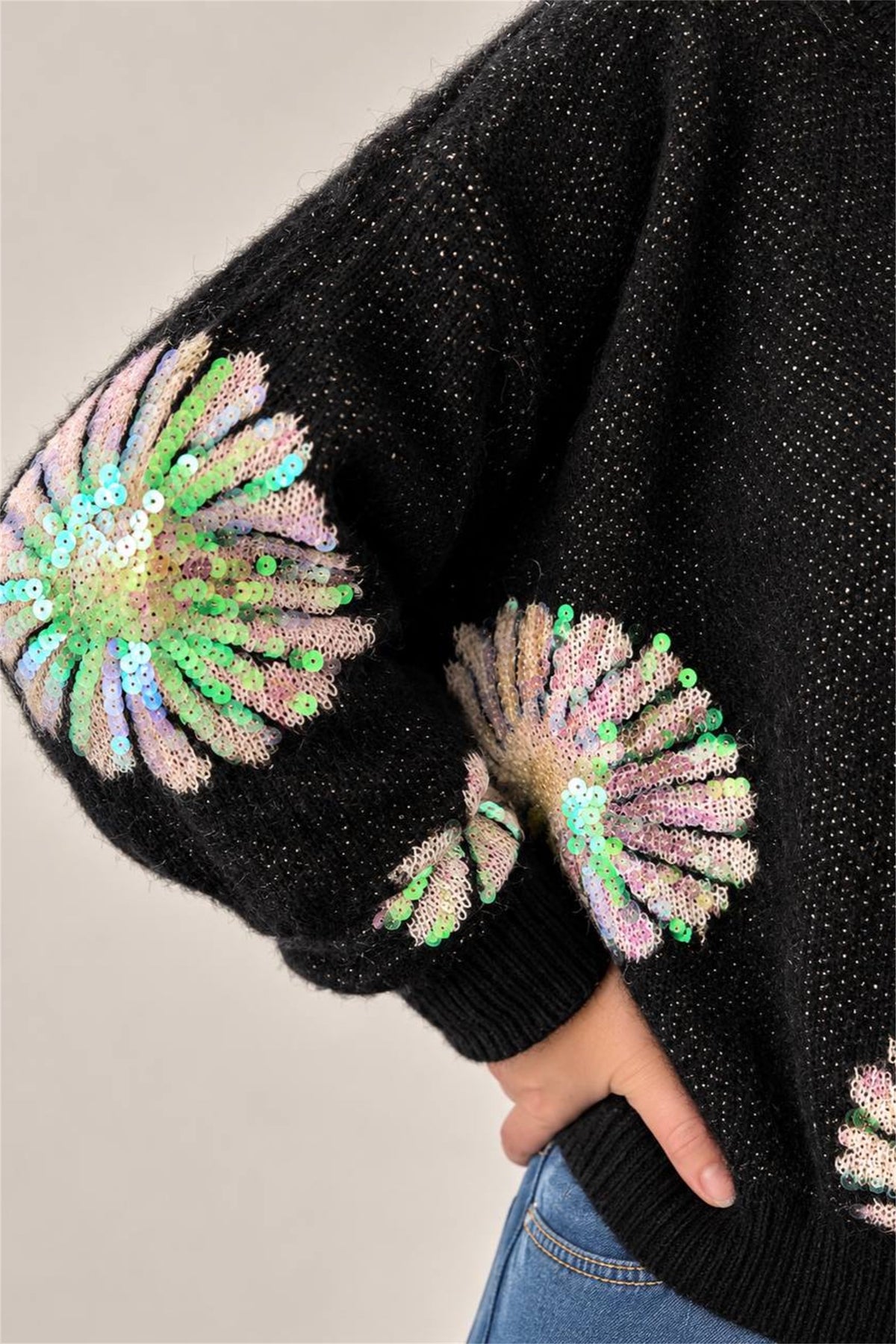 Maglia Kaos, primo piano del ricamo a margherita in paillettes cangianti sulla manica