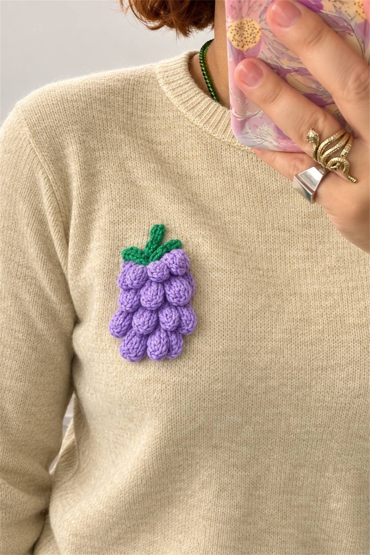 Dettaglio del grappolo d'uva a rilievo applicato sul maglione beige
